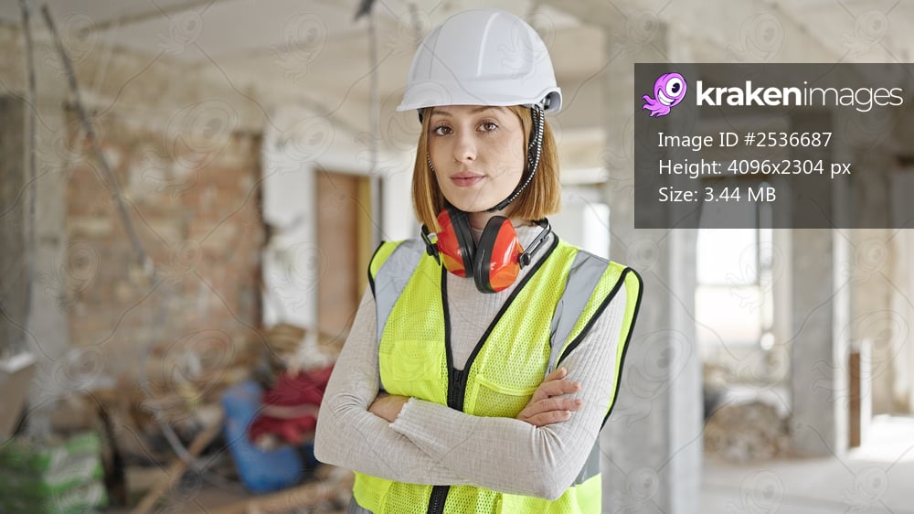 Young blonde woman architect standing with relaxed expression and arms crossed gesture at construction site