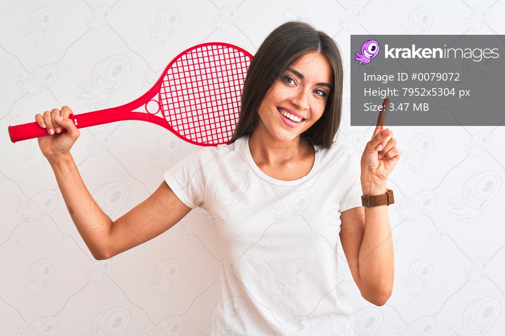 Beautiful sportswoman playing tennis using racket standing over isolated white background very happy pointing with hand and finger to the side
