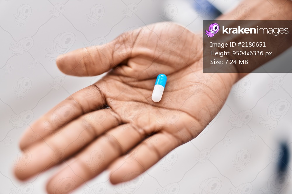 African american woman hand holding pill at clinic