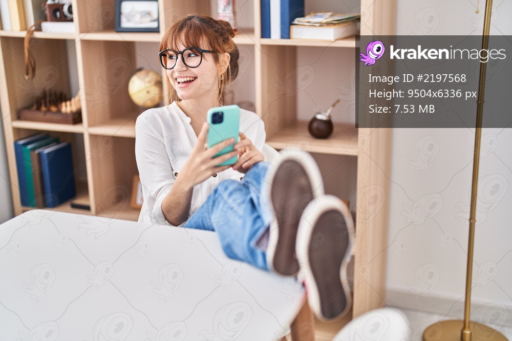 Young woman using smartphone sitting on table at home