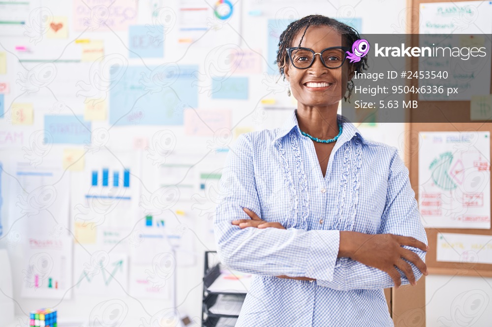 Middle age african american woman business worker smiling confident standing with arms crossed gesture at office