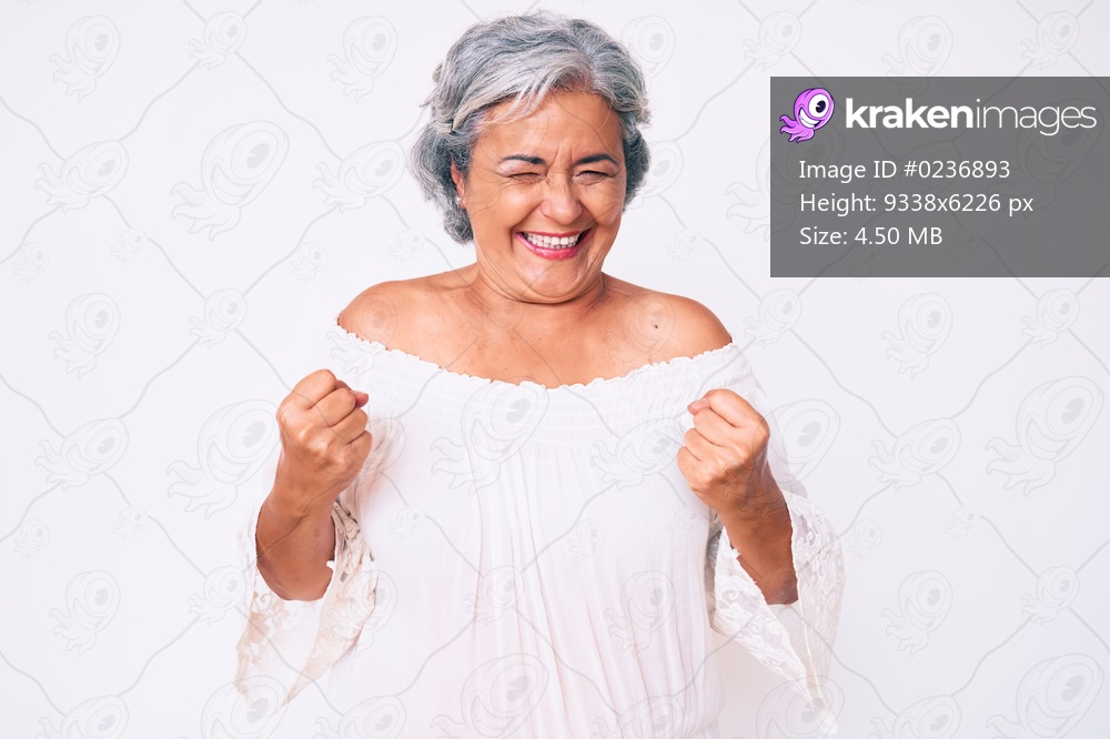 Senior hispanic grey- haired woman wearing casual clothes very happy and excited doing winner gesture with arms raised, smiling and screaming for success. celebration concept. 