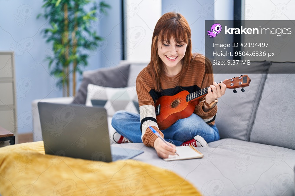 Young woman composing song playing ukelele at home
