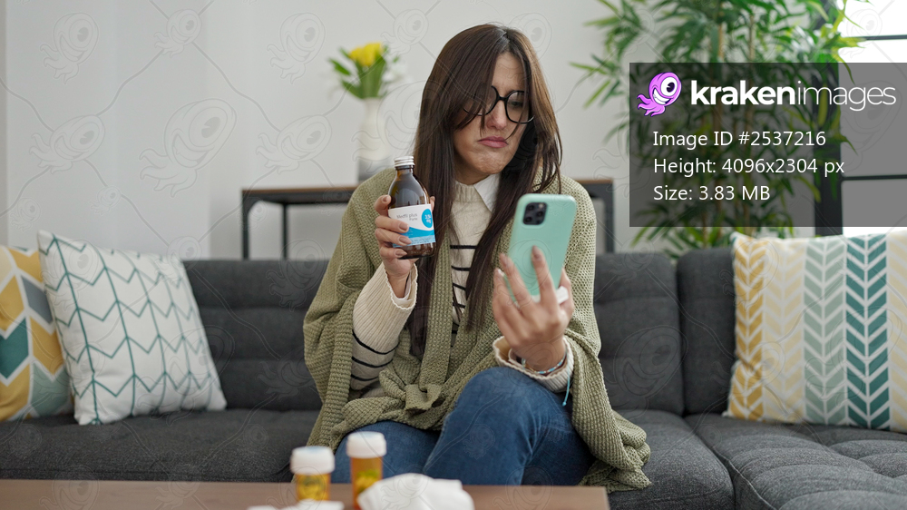 Young beautiful hispanic woman having medical video call consultation showing medicine bottle at home