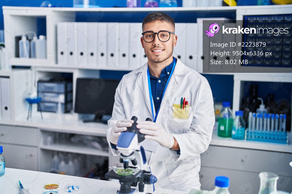 Young hispanic man scientist smiling confident working at laboratory