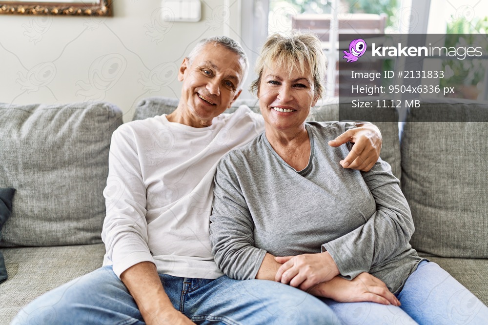 Senior caucasian couple smiling happy and hugging sitting on the sofa at home.