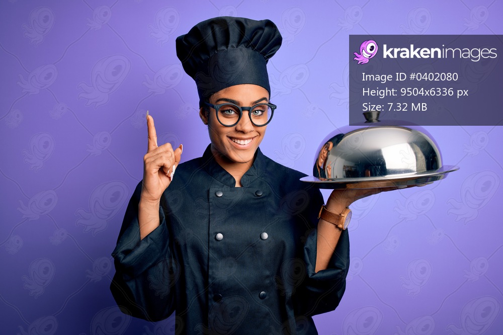 Young african american cooker girl wearing uniform and hat holding tray with dome surprised with an idea or question pointing finger with happy face, number one