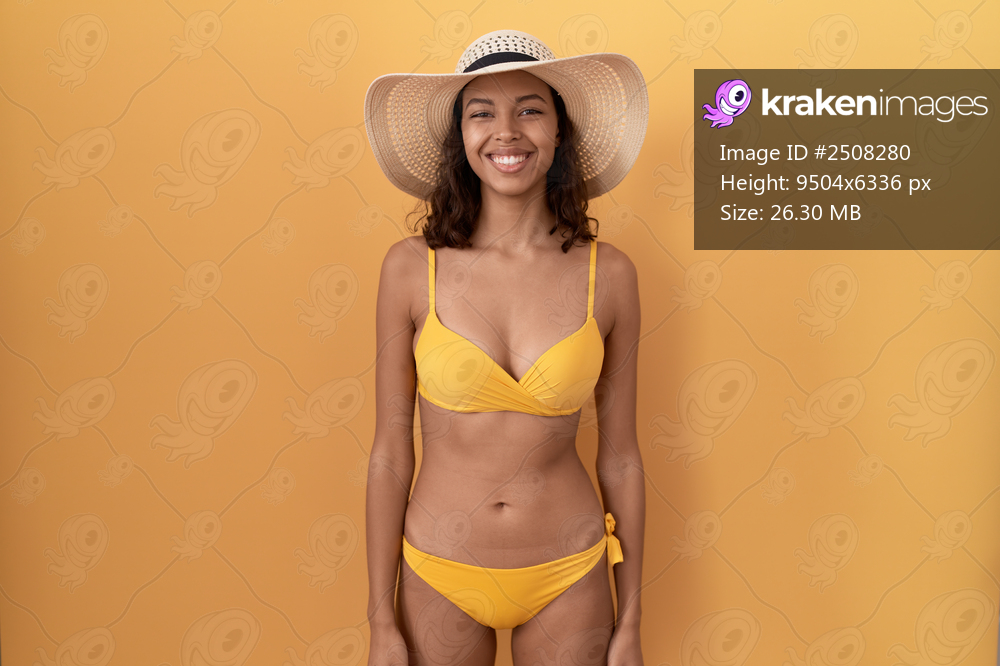 Young hispanic woman wearing bikini and summer hat with a happy and cool smile on face. lucky person. 