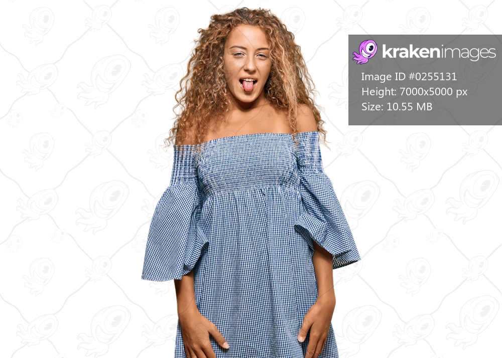 Beautiful caucasian teenager girl wearing summer dress sticking tongue out happy with funny expression. emotion concept. 