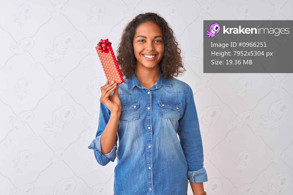 Young brazilian woman holding valentine gift standing over isolated white background with a happy face standing and smiling with a confident smile showing teeth