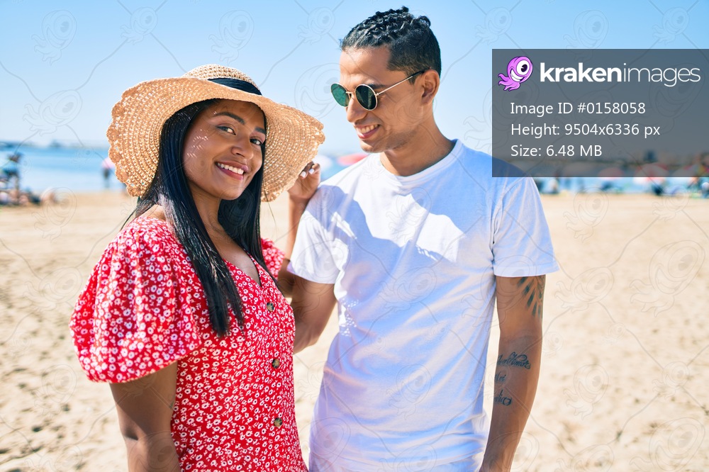Young latin couple smiling happy and hugging at the beach.