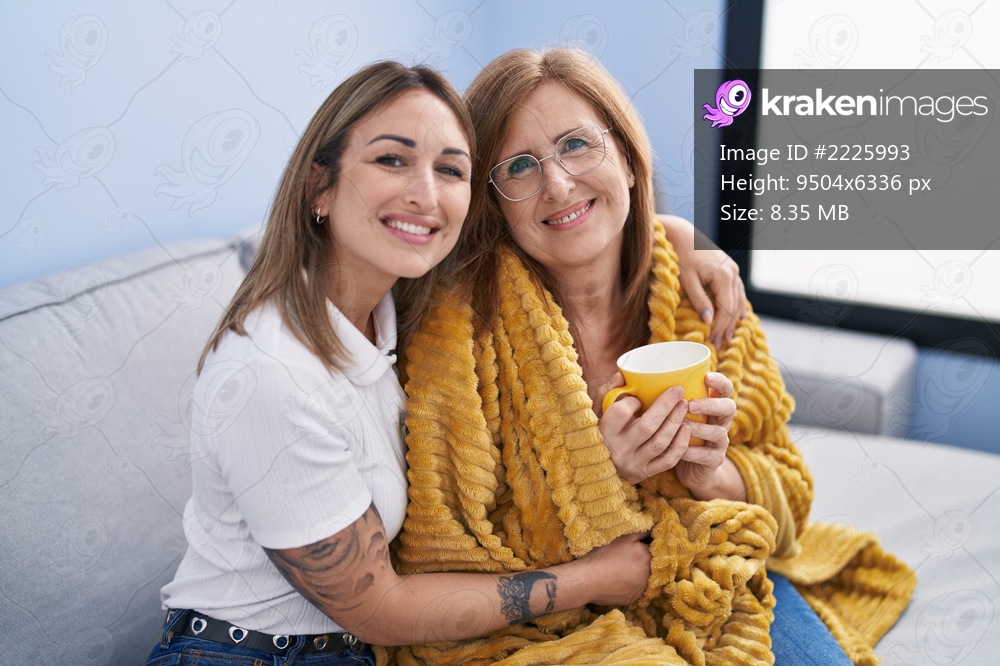 Mother and daughter hugging each other drinking coffee at home