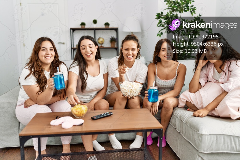 Group of young hispanic women celebrating pajamas party watching movie at home.
