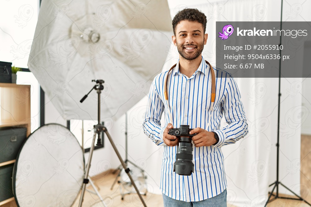 Young arab photographer man smiling happy using reflex camera at photo studio.