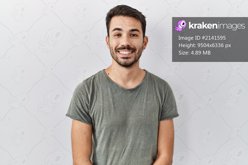 Young hispanic man with beard wearing casual t shirt over white background with a happy and cool smile on face. lucky person. 