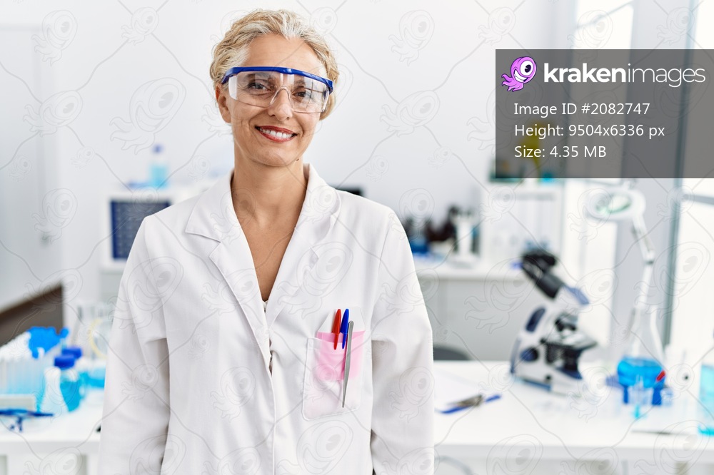 Middle age blonde woman working at scientist laboratory with a happy and cool smile on face. lucky person. 
