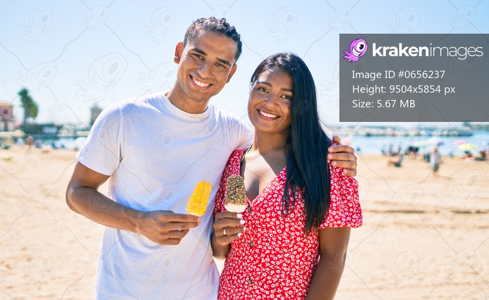 Young latin couple smiling happy eating ice cream at the beach.