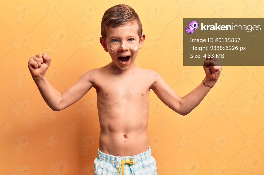 Cute blond kid wearing swimwear screaming proud, celebrating victory and success very excited with raised arms 