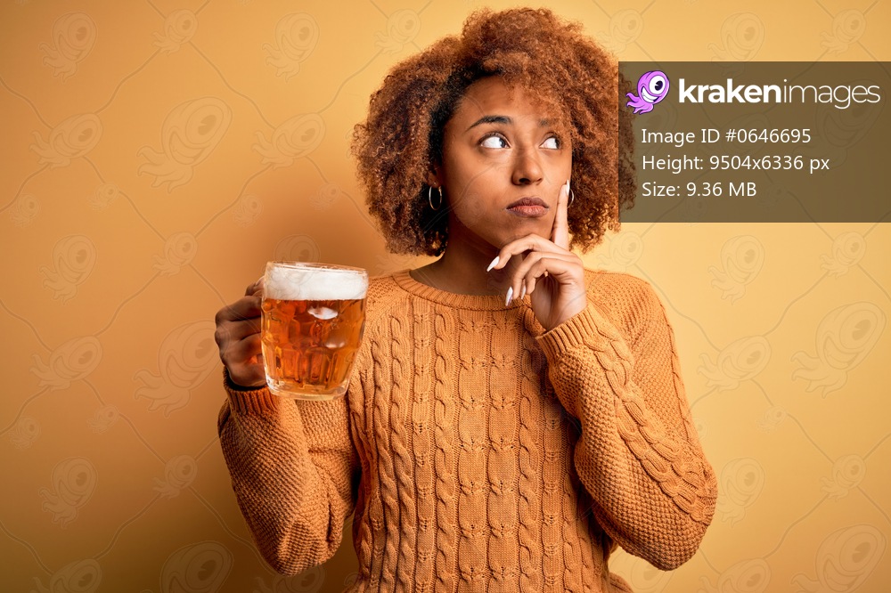 Young beautiful African American afro woman with curly hair drinking jar of beer serious face thinking about question, very confused idea