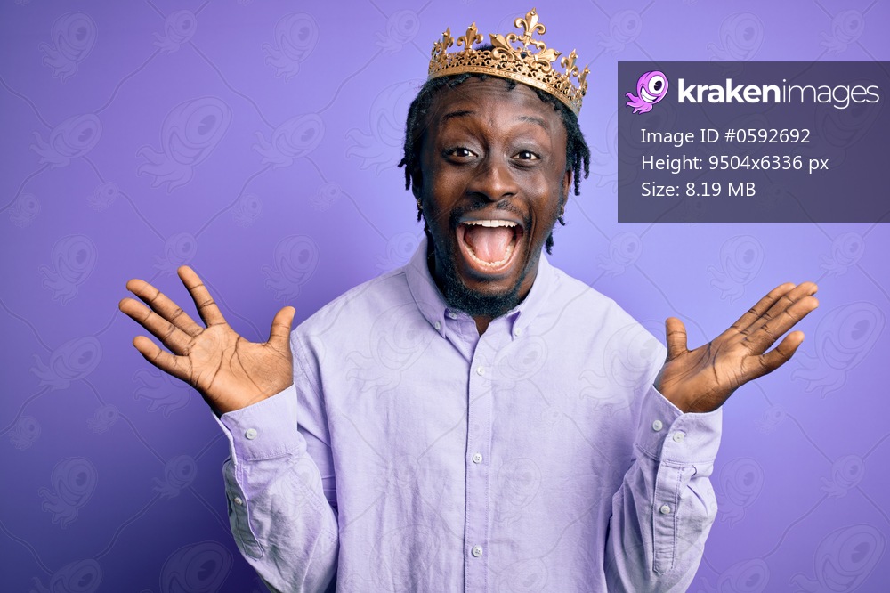 Young african american man wearing golden crown of king over isolated purple background celebrating crazy and amazed for success with arms raised and open eyes screaming excited. Winner concept