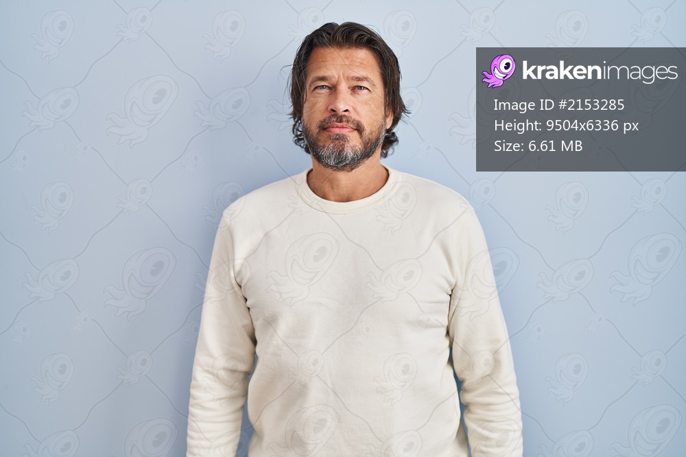 Handsome middle age man wearing casual sweater over blue background relaxed with serious expression on face. simple and natural looking at the camera. 