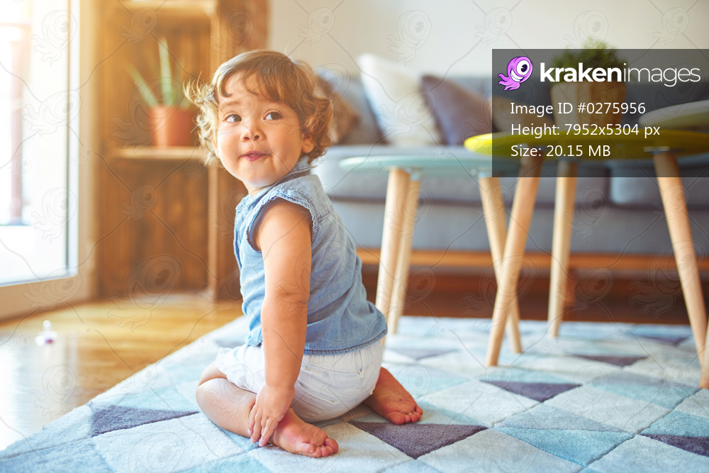 Beautiful toddler child girl wearing denim shirt sitting on the carpet