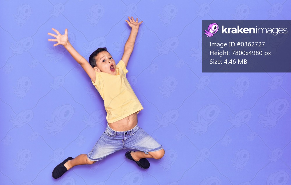 Adorable kid wearing casual clothes jumping over isolated purple background