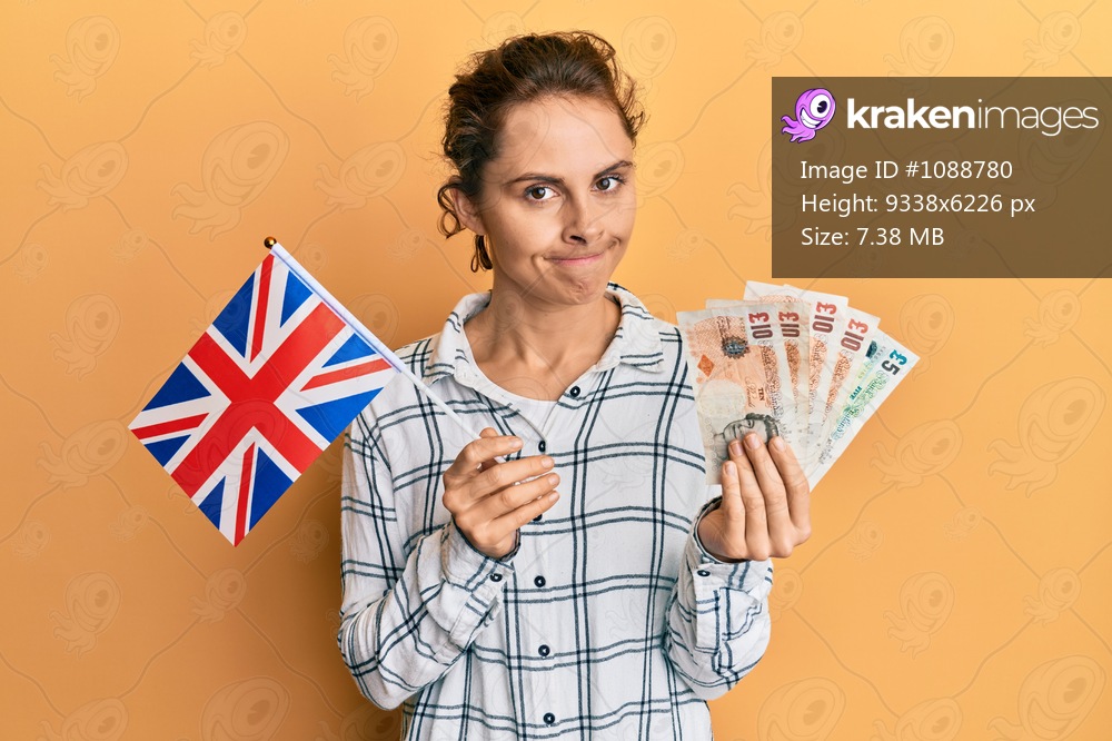 Young brunette woman holding uk flag and pounds banknotes skeptic and nervous, frowning upset because of problem. negative person. 