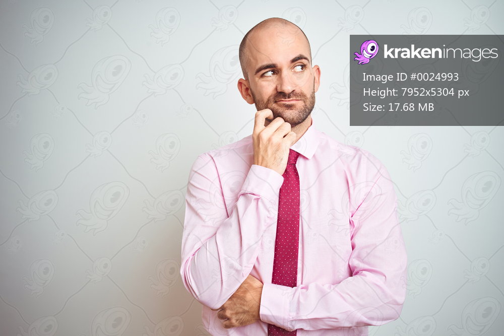 Young business man wearing pink tie over isolated background with hand on chin thinking about question, pensive expression. Smiling with thoughtful face. Doubt concept.