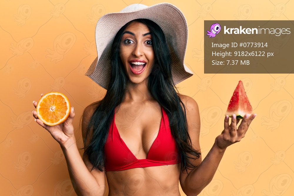 Beautiful hispanic woman eating watermelon and orange celebrating crazy and amazed for success with open eyes screaming excited. 