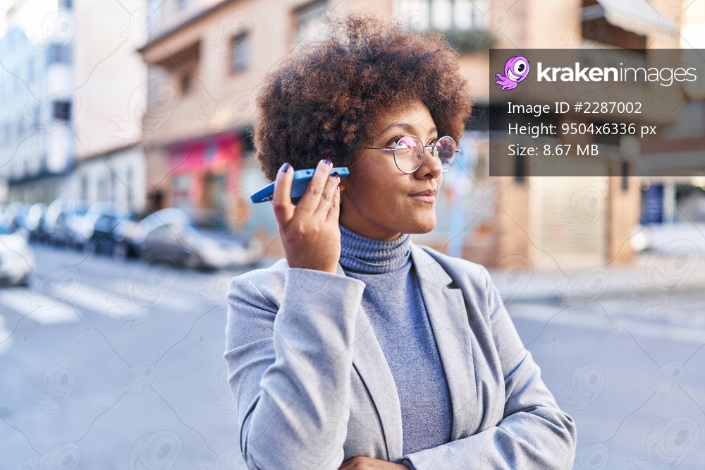 African american woman executive listening voice message by smartphone at street