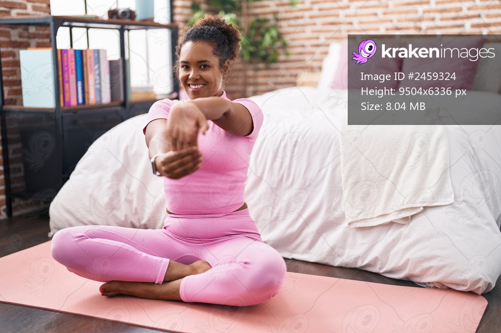 African american woman smiling confident stretching arm at bedroom