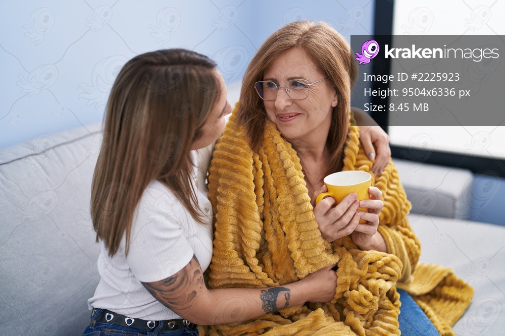 Mother and daughter hugging each other drinking coffee at home