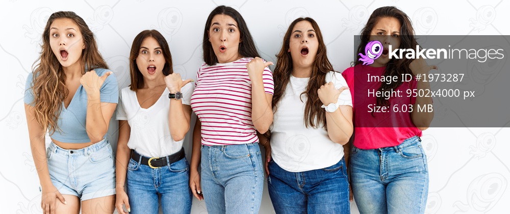 Group of women wearing casual clothes standing over isolated background surprised pointing with hand finger to the side, open mouth amazed expression. 