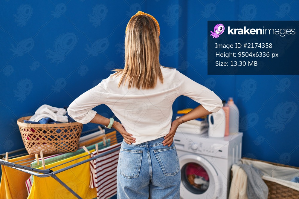 Young blonde woman at laundry room standing backwards looking away with arms on body 
