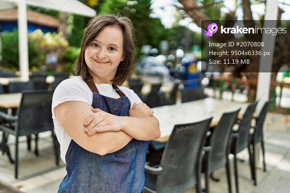 Young down syndrome woman smiling confident wearing apron at coffee shop terrace