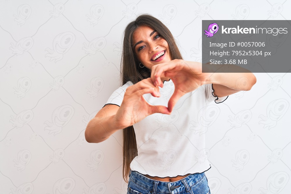 Young beautiful woman wearing casual t-shirt standing over isolated white background smiling in love showing heart symbol and shape with hands. Romantic concept.