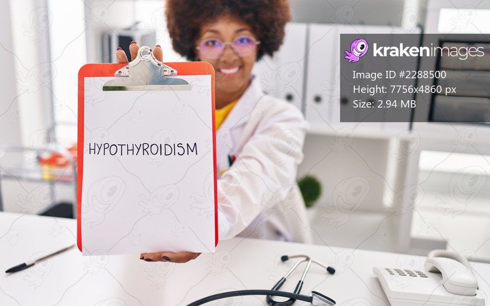 African american woman wearing doctor uniform holding clipboard with hypothyroidism message at clinic
