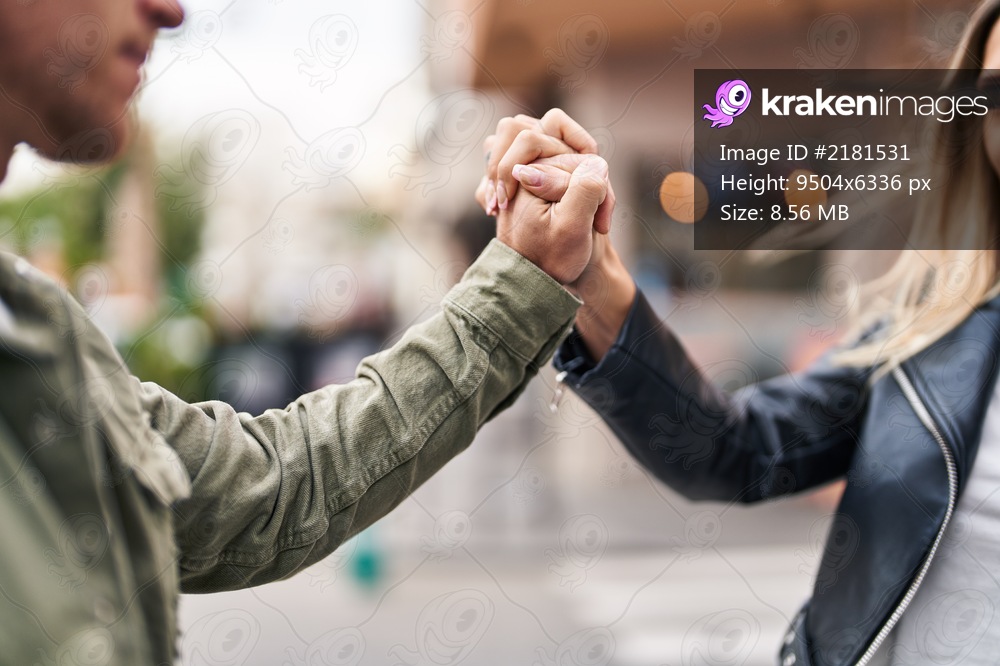 Man and woman couple standing with hands together at street