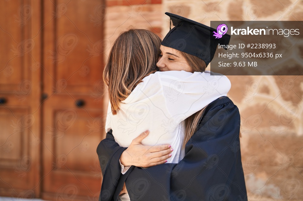 Two women mother and graduated daughter hugging each other at campus university