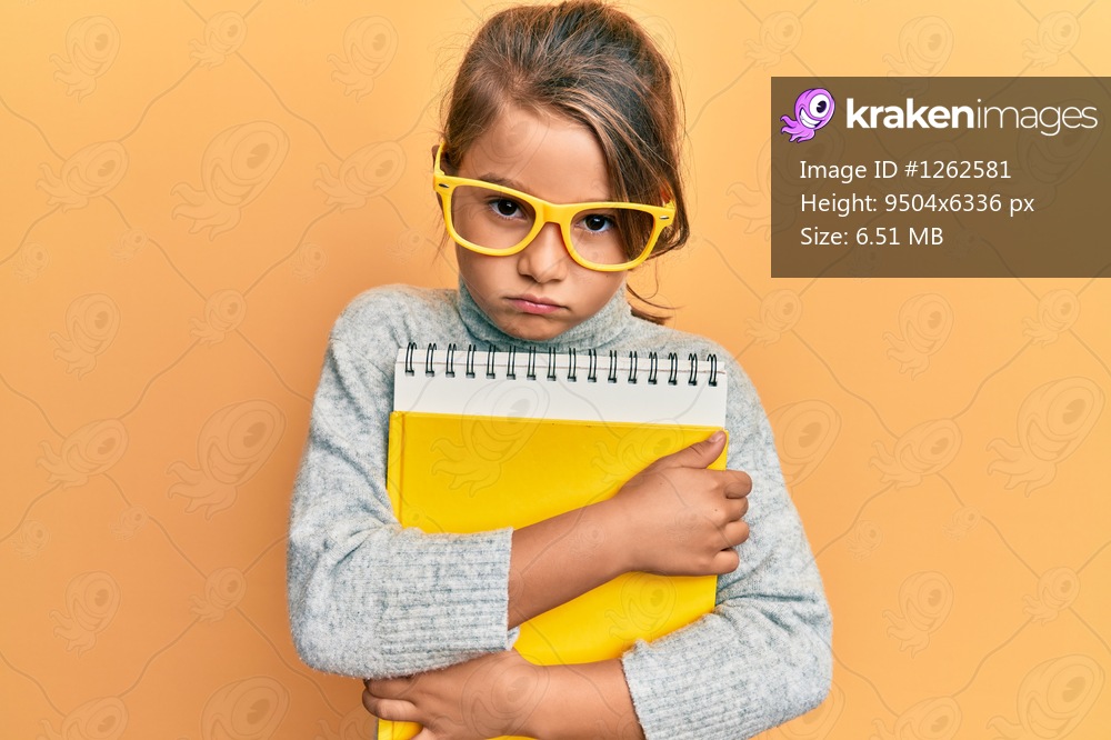 Little beautiful girl wearing glasses and holding books skeptic and nervous, frowning upset because of problem. negative person. 