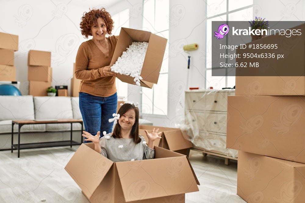 Mature mother and down syndrome daughter moving to a new home, having fun with cardboard foam