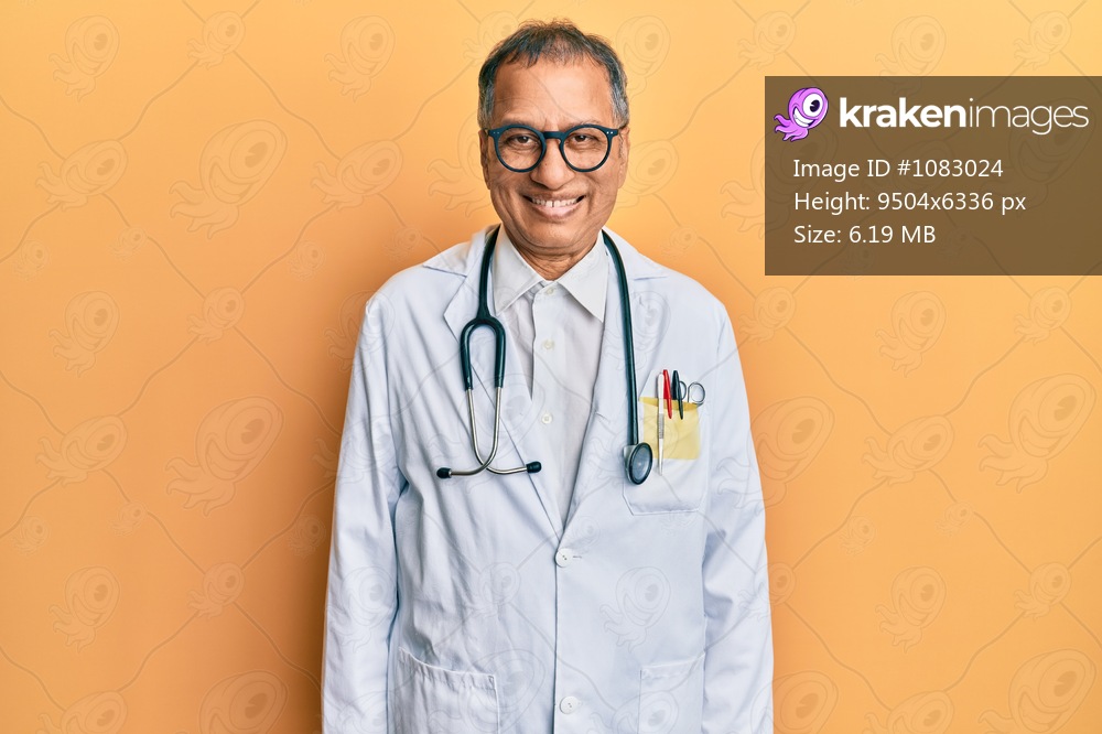 Middle age indian man wearing doctor coat and stethoscope with a happy and cool smile on face. lucky person. 