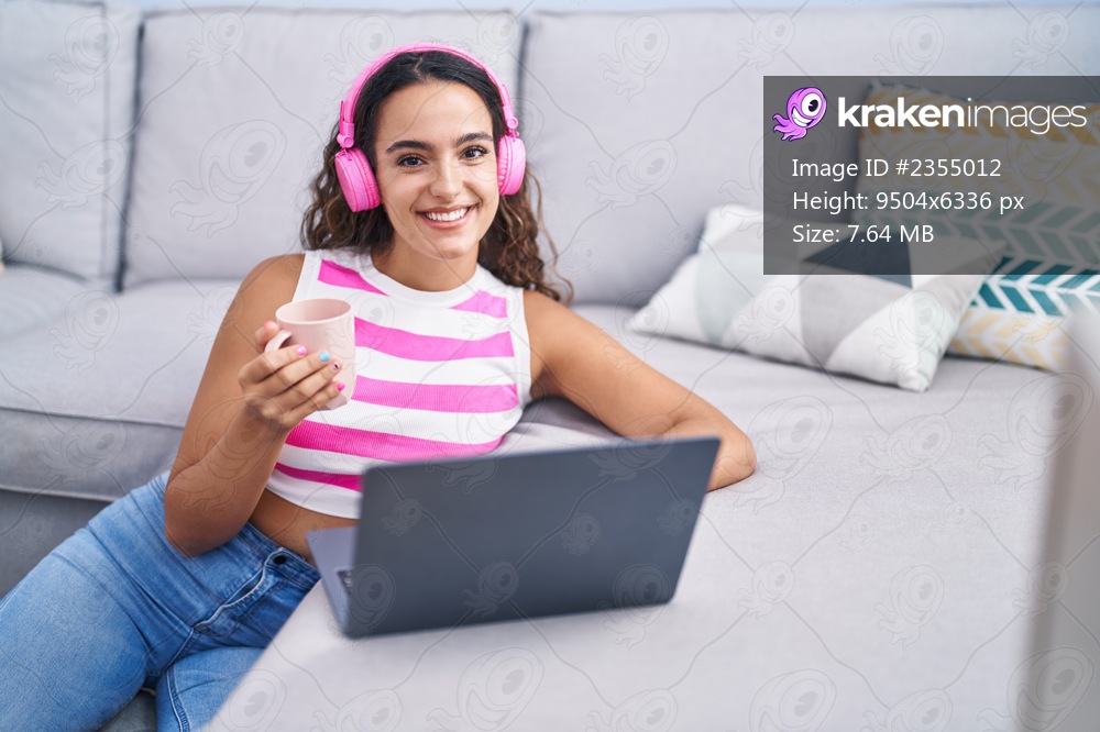 Young beautiful hispanic woman listening to music drinking coffee at home