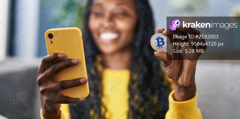 African american woman using smartphone and bitcoin at home