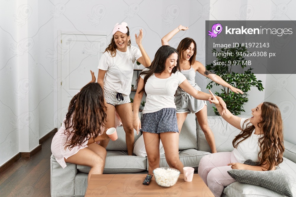 Group of young hispanic women celebrating pajamas party dancing at home.