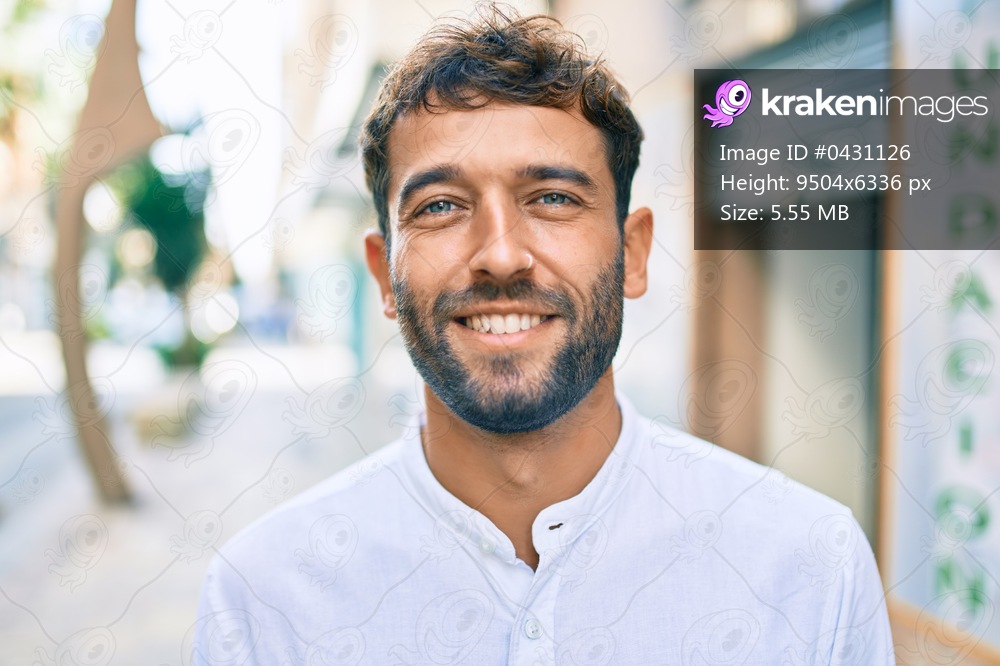 Handsome man with beard wearing casual white shirt on a sunny day smiling happy outdoors
