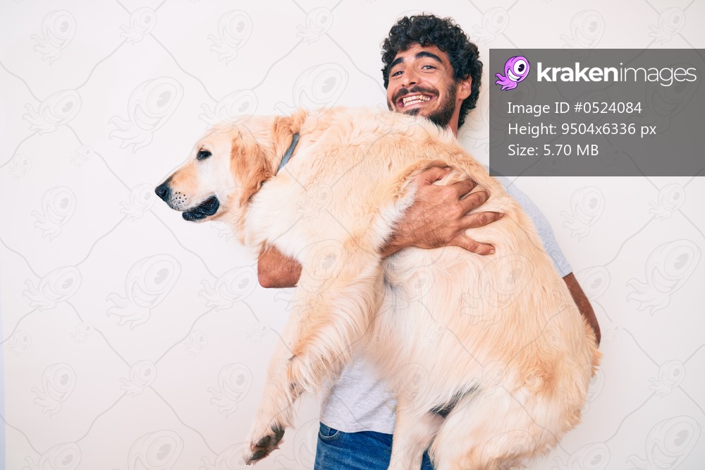 Young handsome man holding and hugging labrador retriever dog, smiling with love to his best friend
